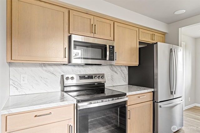 kitchen with light brown cabinetry, decorative backsplash, stainless steel appliances, and light stone counters