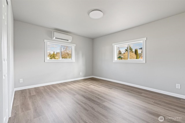 empty room featuring baseboards, an AC wall unit, and wood finished floors