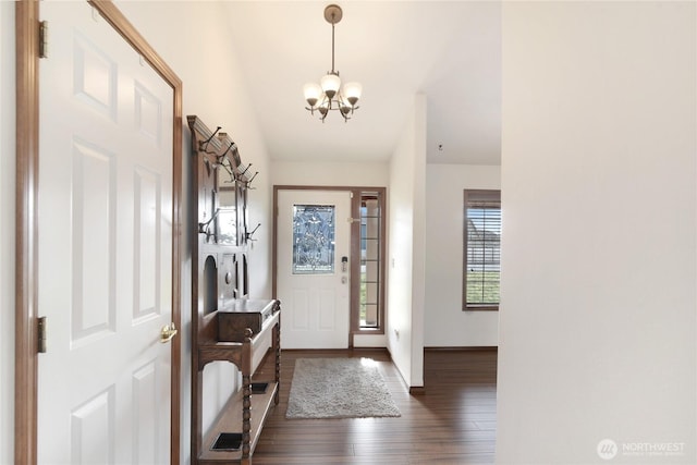 foyer entrance with dark wood finished floors and an inviting chandelier