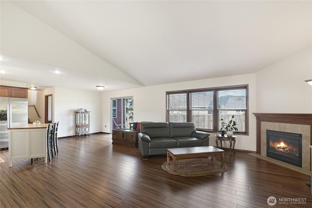 living area featuring baseboards, a fireplace, high vaulted ceiling, and wood finished floors