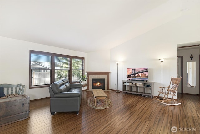 living room with lofted ceiling, baseboards, dark wood finished floors, and a tiled fireplace