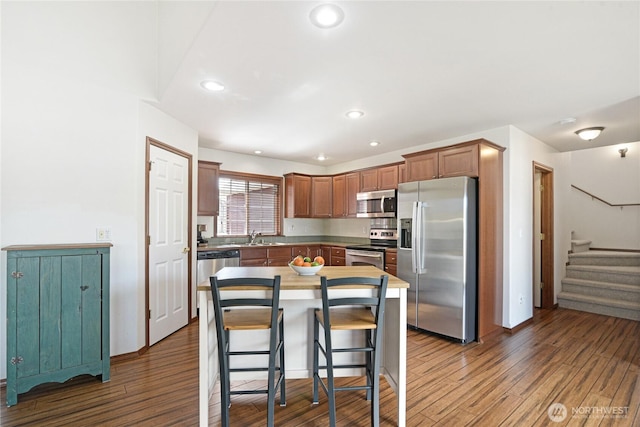 kitchen featuring stainless steel appliances, a sink, a breakfast bar area, and wood finished floors