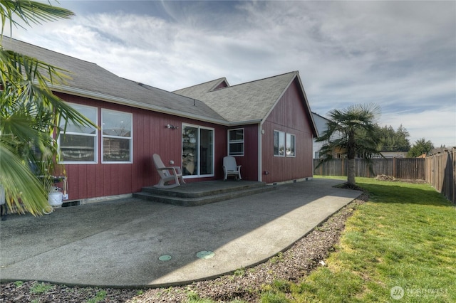 back of house featuring a patio, a shingled roof, a lawn, and fence