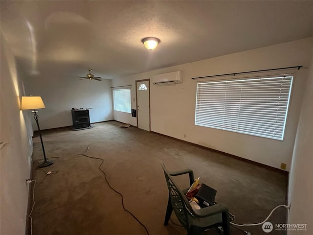 unfurnished living room featuring a ceiling fan, a wall mounted AC, a wood stove, and baseboards