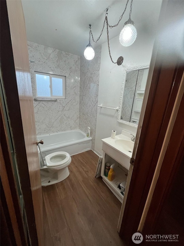 full bath with toilet, shower / tub combination, wood finished floors, and vanity