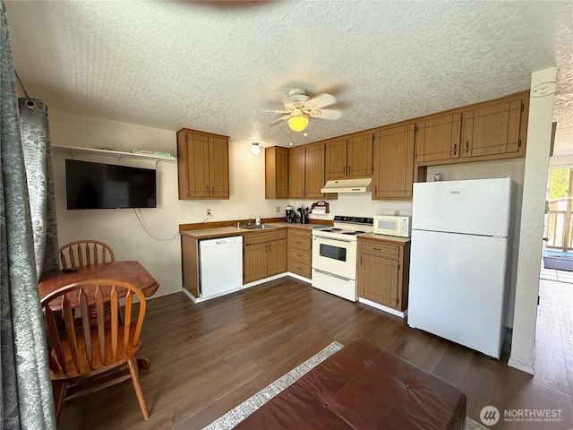 kitchen with white appliances, dark wood finished floors, a ceiling fan, under cabinet range hood, and a sink