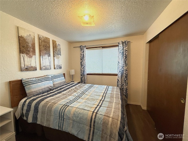 bedroom featuring a closet, a textured ceiling, wood finished floors, and a textured wall