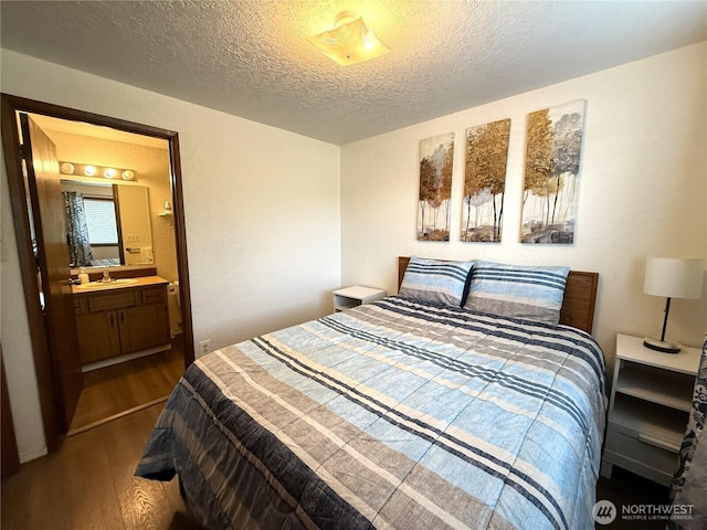 bedroom with dark wood-style floors, a sink, a textured ceiling, and ensuite bathroom