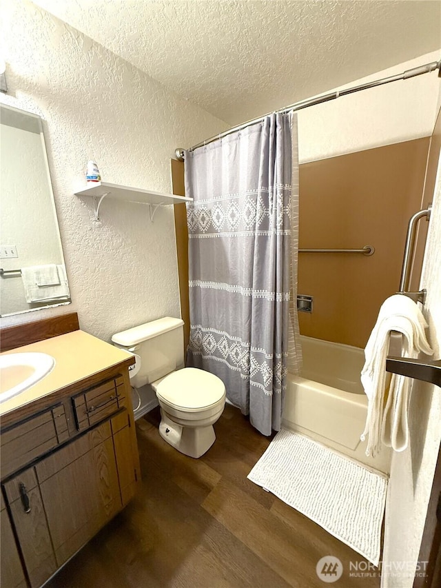 bathroom featuring a textured wall, toilet, vanity, a textured ceiling, and wood finished floors