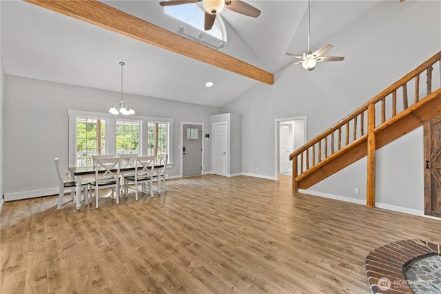 dining space with light wood finished floors, ceiling fan with notable chandelier, stairs, and baseboards