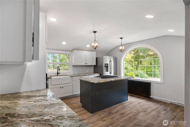 kitchen featuring radiator, light stone countertops, lofted ceiling, stainless steel appliances, and white cabinets