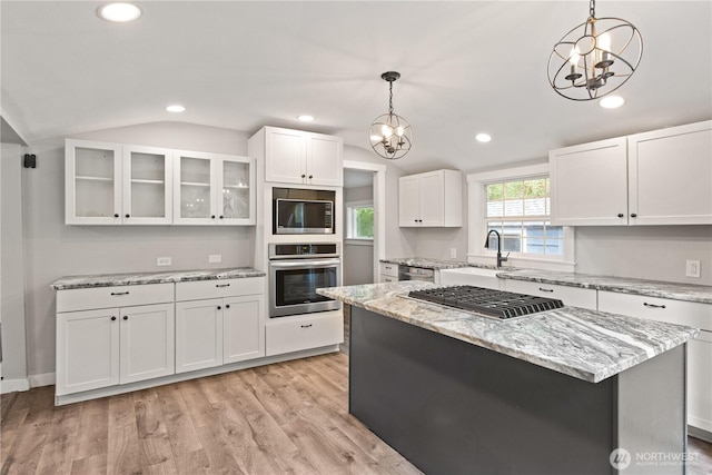 kitchen with glass insert cabinets, lofted ceiling, light wood-style floors, white cabinets, and stainless steel appliances