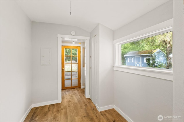 hall with baseboards, wood finished floors, and vaulted ceiling