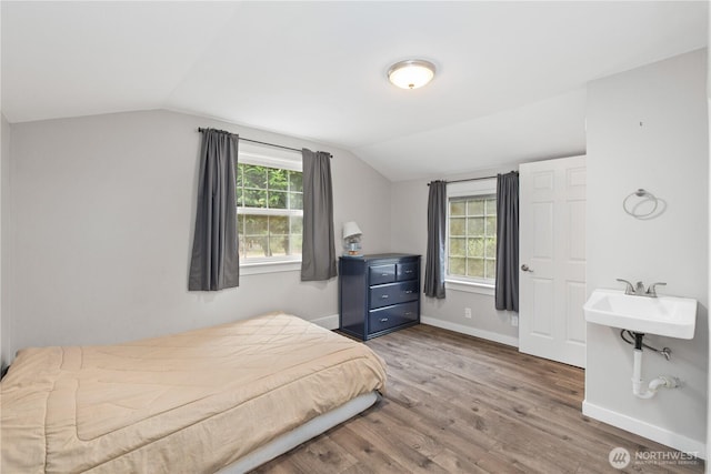 bedroom with lofted ceiling, wood finished floors, and baseboards