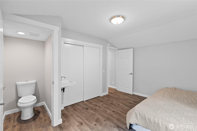 bedroom with a closet, baseboards, lofted ceiling, and wood finished floors