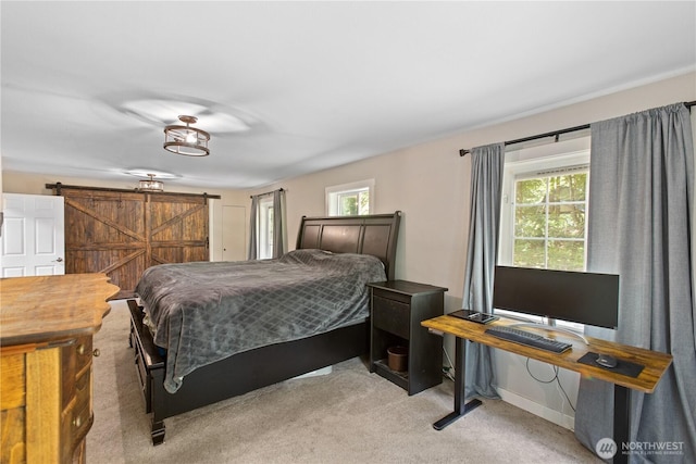 bedroom with baseboards, a barn door, multiple windows, and light carpet