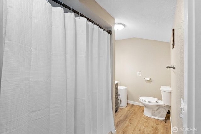 full bath with baseboards, toilet, vaulted ceiling, a shower with curtain, and wood finished floors