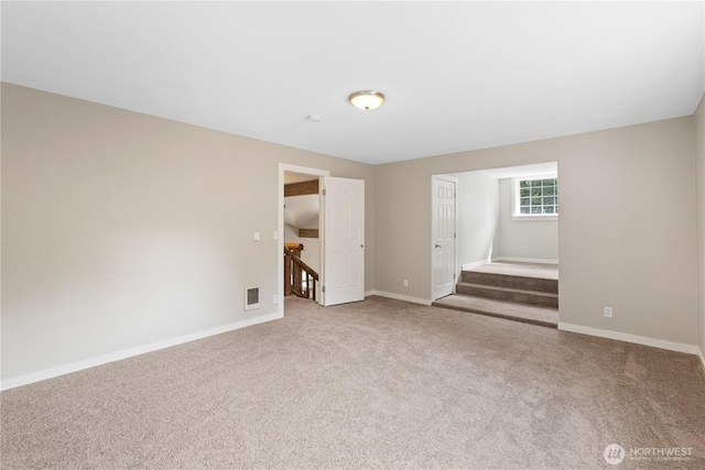 carpeted empty room with stairway, visible vents, and baseboards