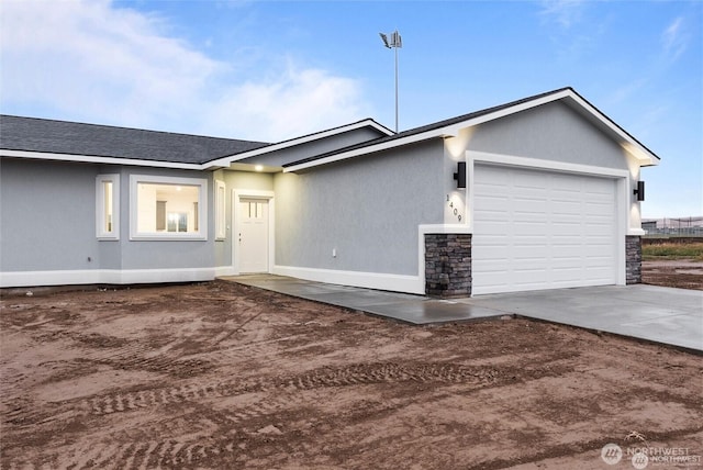 view of front of home with a garage, concrete driveway, stone siding, roof with shingles, and stucco siding