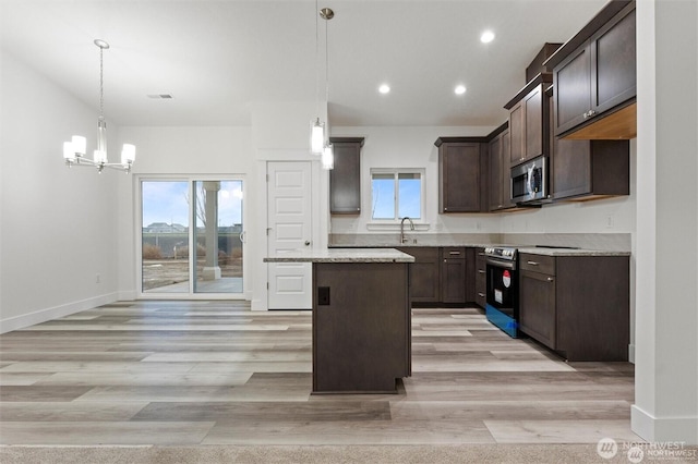 kitchen with light wood-style flooring, appliances with stainless steel finishes, a kitchen island, dark brown cabinetry, and baseboards