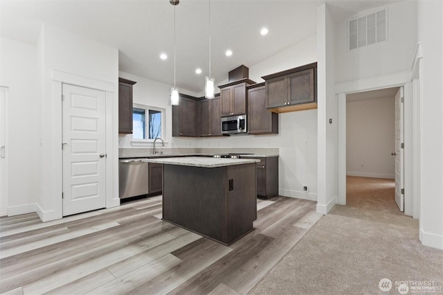 kitchen with a center island, visible vents, appliances with stainless steel finishes, a sink, and dark brown cabinets