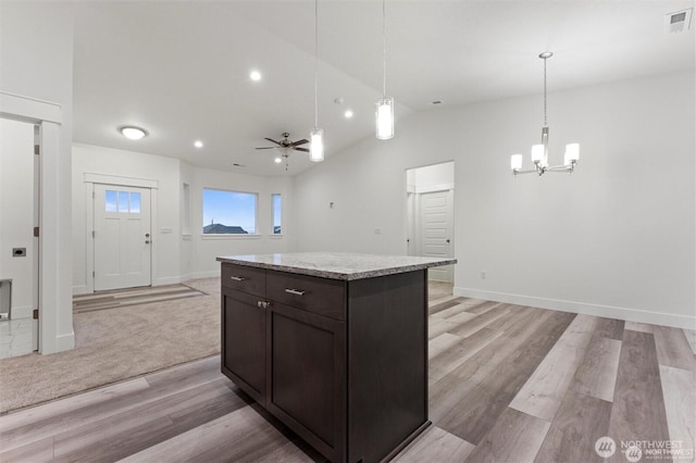 kitchen with hanging light fixtures, light wood-style flooring, open floor plan, a kitchen island, and dark brown cabinetry