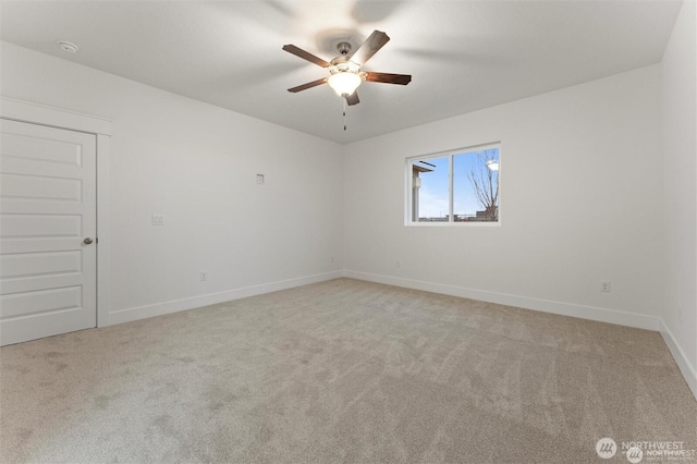 spare room featuring a ceiling fan, light colored carpet, and baseboards