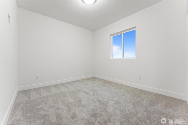 carpeted empty room featuring baseboards