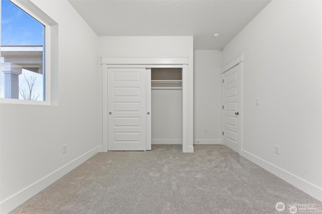 unfurnished bedroom featuring carpet, baseboards, and a closet