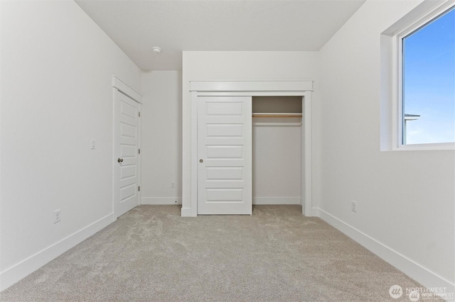 unfurnished bedroom with a closet, baseboards, and carpet flooring