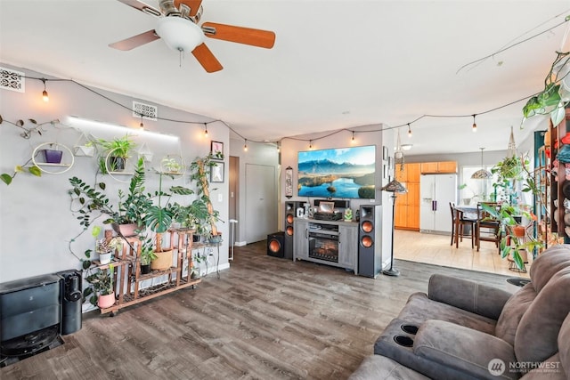 living area featuring a fireplace, light wood finished floors, and ceiling fan