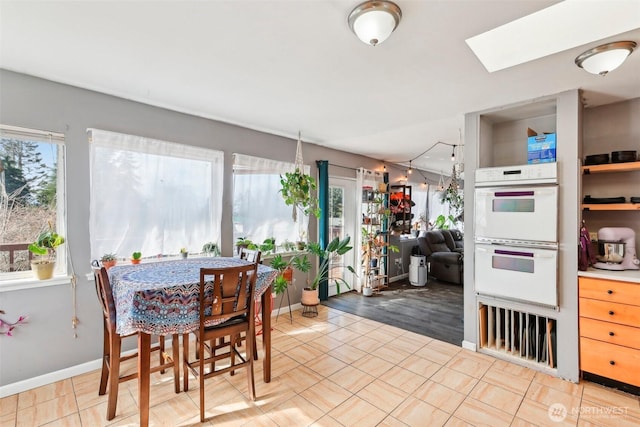 dining area featuring a skylight, a healthy amount of sunlight, and baseboards