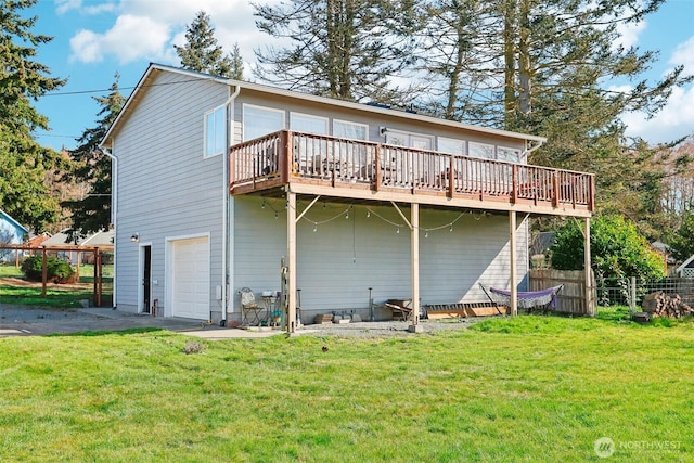 rear view of house with a deck, a yard, and fence