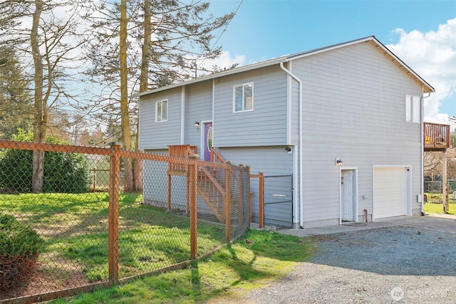 rear view of property with a yard, gravel driveway, a garage, and fence