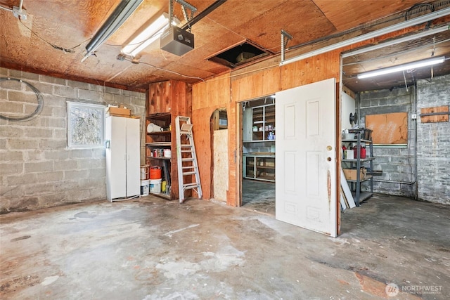 garage with a garage door opener and concrete block wall