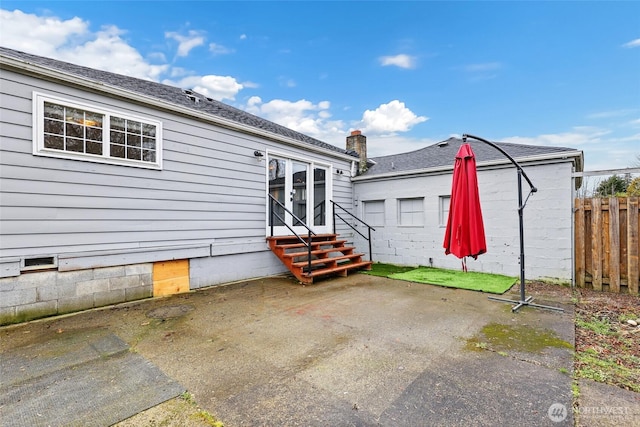 rear view of property with entry steps, a patio area, fence, and roof with shingles