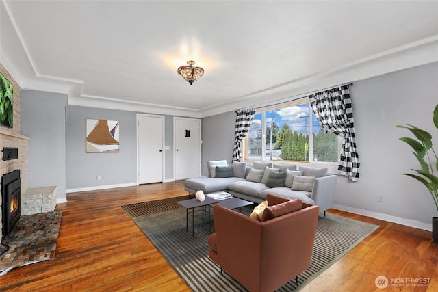 living room featuring a fireplace, baseboards, and wood finished floors