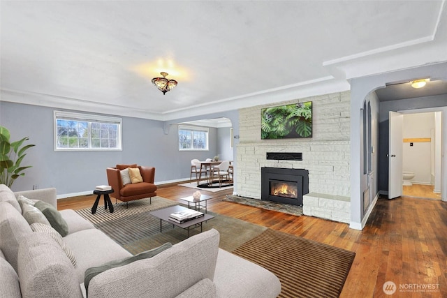 living area with a stone fireplace, baseboards, and wood finished floors