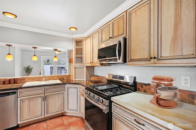 kitchen featuring light tile patterned floors, a ceiling fan, appliances with stainless steel finishes, crown molding, and a sink