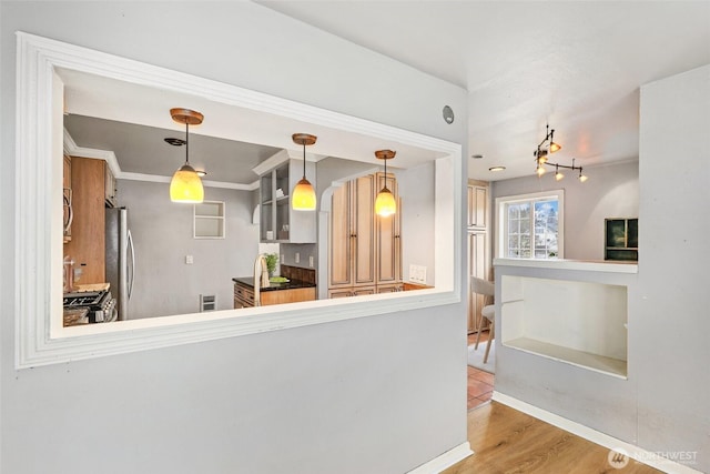 kitchen featuring stainless steel appliances, pendant lighting, crown molding, and wood finished floors