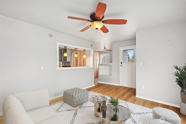 living area with ceiling fan, baseboards, and wood finished floors