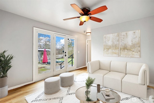 living area with ceiling fan, baseboards, and wood finished floors