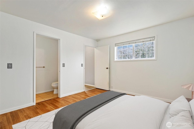 bedroom with baseboards, light wood finished floors, and ensuite bathroom