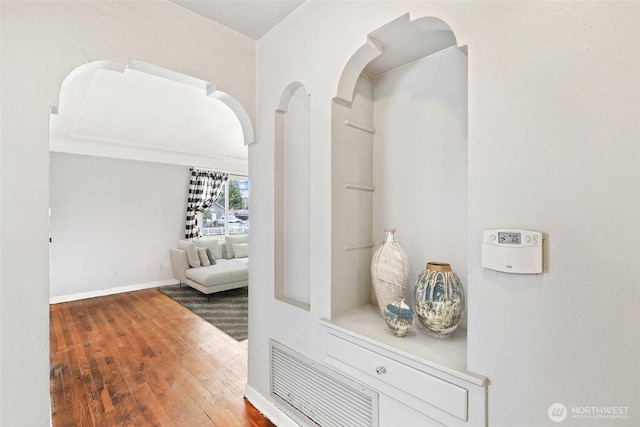 hall featuring hardwood / wood-style flooring, visible vents, and baseboards