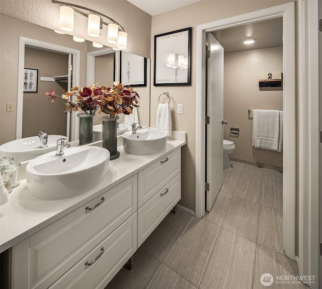 bathroom with double vanity, a sink, and toilet