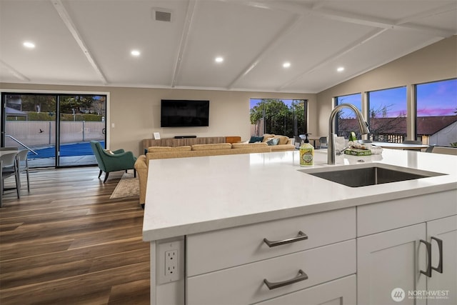 kitchen with vaulted ceiling with beams, a wealth of natural light, light countertops, and a sink