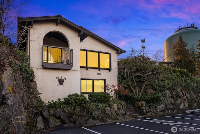 exterior space featuring uncovered parking, a balcony, and stucco siding