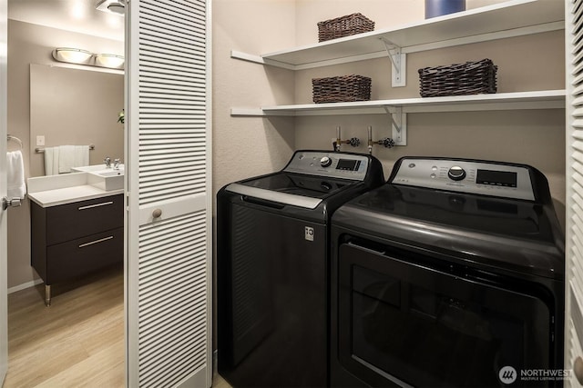 laundry room with laundry area, a sink, baseboards, independent washer and dryer, and light wood finished floors