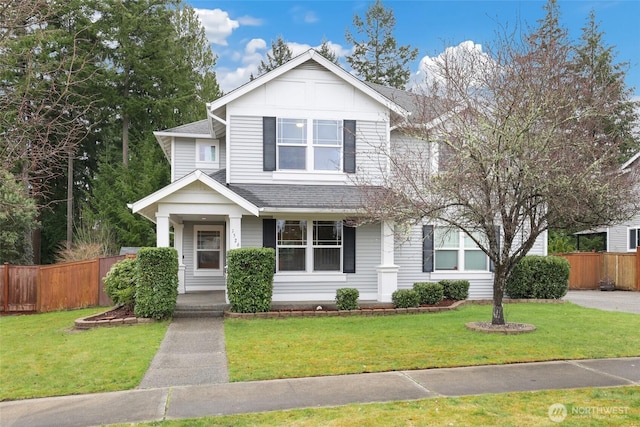 view of front of property featuring roof with shingles, a front lawn, and fence