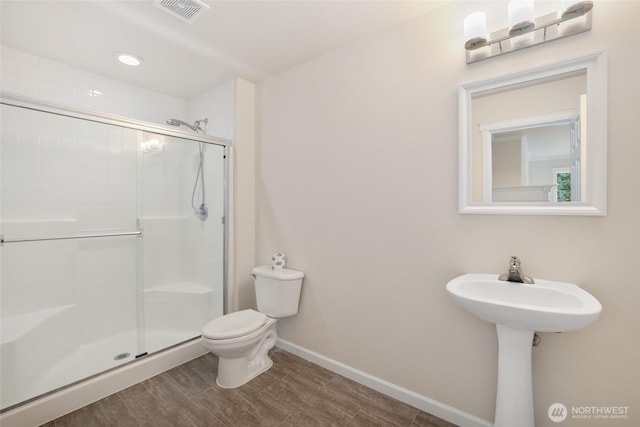 bathroom featuring visible vents, toilet, wood finished floors, a shower stall, and baseboards